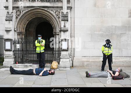 La police se tient aux côtés d'un manifestant pendant une manifestation de la rébellion en voie d'extinction dans le centre de Londres. Le groupe de la campagne environnementale a prévu de tenir des marches dans plusieurs sites de la capitale, avant de déménager sur la place du Parlement à Westminster. Banque D'Images