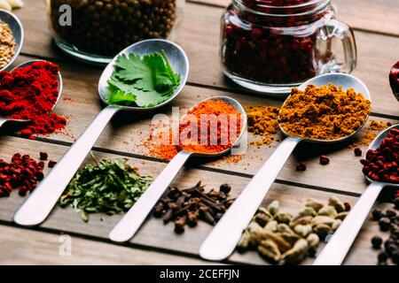 Bande d'assorted spices placés en ordre sur le bois de la table près de bouteille d'huile Banque D'Images