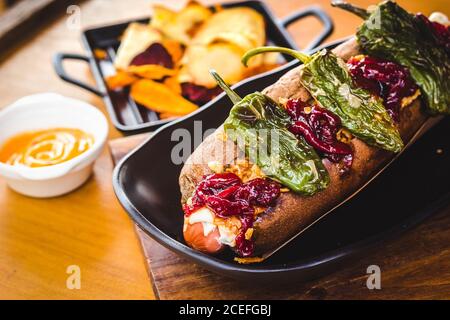 Gros plan d'un délicieux hot dog créatif et garni de poivrons séchés au soleil. Banque D'Images