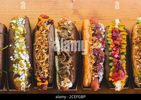 Rangée de hot dogs assortis avec différentes garnitures et garnitures délicieuses sur bois. Banque D'Images