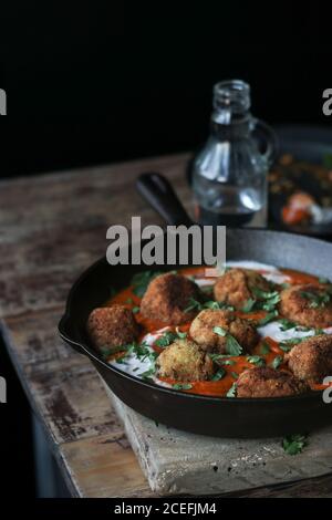 Bouteille d'eau en verre sur la table de bois près de bouillie boulettes de riz et de viande délicieuse avec persil et sauce Banque D'Images