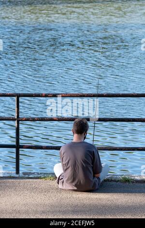 Un jeune homme non identifié pêche dans le lac à Kissena Park à Flushing, Queens, New York. Banque D'Images