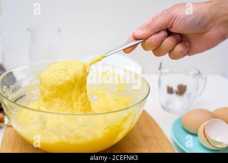 la pâte pour cupcakes faite de farine de riz, beurre, oeufs, sucre coule de la cuillère. gros plan de la texture de la pâte dans un plat transparent. Banque D'Images