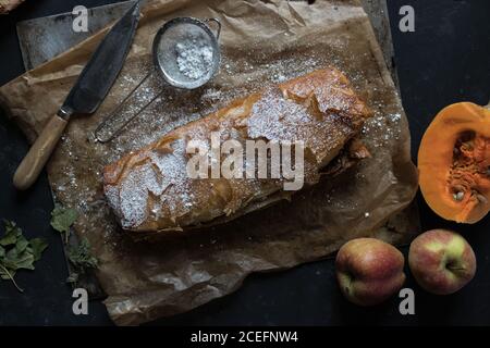 Du dessus de la photo d'un couteau tranchant allongé sur le parchemin à proximité délicieux strudel de citrouille et de pomme Banque D'Images