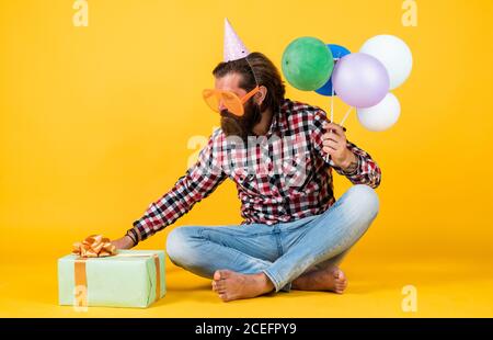 cadeau ouvert. hipster souriant avec joie. amusez-vous à la fête. préparez-vous pour les vacances. Event Manager pose avec un accessoire festif. Concept amusant et heureux. Homme heureux tenant des ballons d'hélium colorés. Banque D'Images