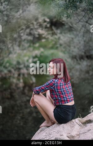 Jolie fille rouge aux cheveux repose près de la rivière. Banque D'Images