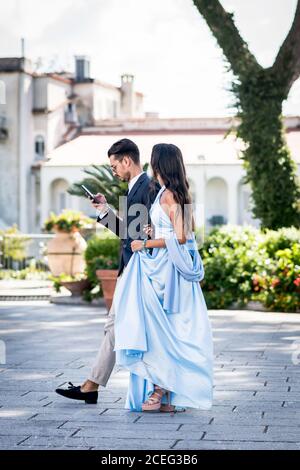 Un beau et élégant couple italien font leur chemin de l'autre côté de la place de la ville pour assister à un mariage. Ravello, Italie. Banque D'Images