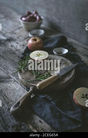 Romarin frais et couteau tranchant couché sur la table de bois près pomme mûre Banque D'Images