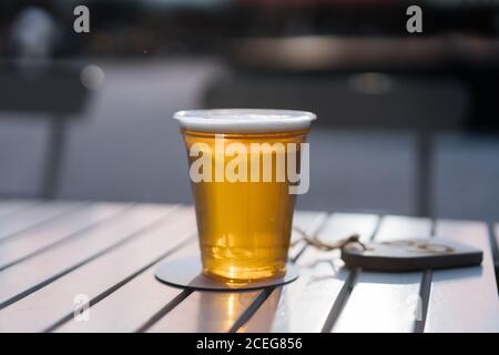 Gros plan d'une tasse en plastique remplie de bière jusqu'au bord et servi sur des montagnes russes sur une table à l'extérieur Banque D'Images