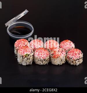 Un délicieux rouleau de Yaki traditionnel frais sur fond noir et réfléchissant. Roulé à sushis avec riz, fromage à la crème, avocat, saumon. Californie Banque D'Images