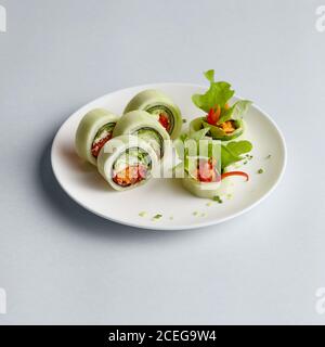 Délicieux petits pains à sushis japonais aux couleurs vives avec du saumon dans du poisson volant caviar magnifiquement fixé sur plaque blanche sur fond blanc de ci-dessus Banque D'Images