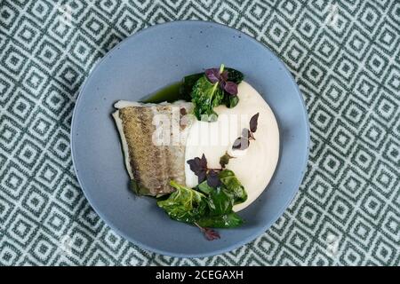 Plat d'assiette bleue avec filet de poisson et sauce Vert dans le style nordique servi sur le tissu Banque D'Images