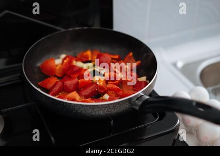 Crop femelle main remuant avec une spatule en bois feuilles de légumes hachées être cuisiné en pot sur cuisinière à gaz Banque D'Images