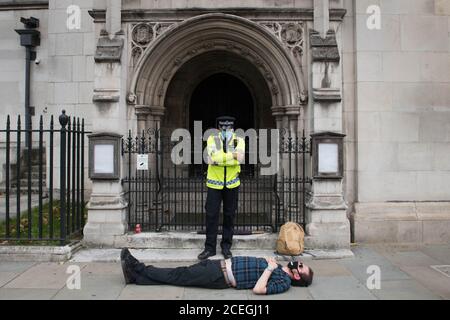 La police se tient à côté des manifestants arrêtés lors d'une manifestation de la rébellion en voie d'extinction dans le centre de Londres. Le groupe de la campagne environnementale a prévu de tenir des marches dans plusieurs sites de la capitale, avant de déménager sur la place du Parlement à Westminster. Banque D'Images