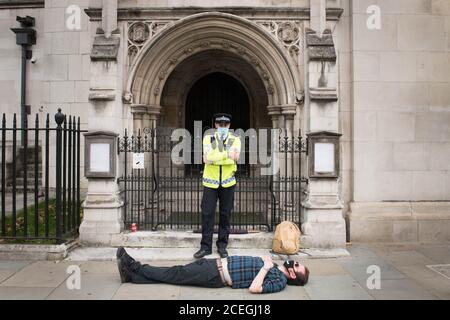 La police se tient à côté des manifestants arrêtés lors d'une manifestation de la rébellion en voie d'extinction dans le centre de Londres. Le groupe de la campagne environnementale a prévu de tenir des marches dans plusieurs sites de la capitale, avant de déménager sur la place du Parlement à Westminster. Banque D'Images