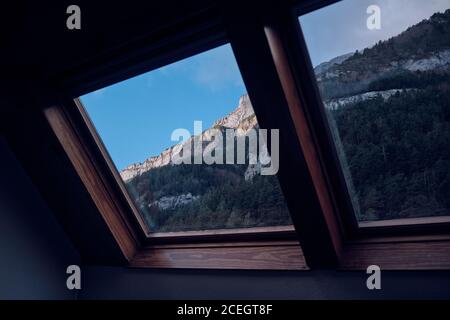 Vue pittoresque sur la majestueuse pente de montagne le jour ensoleillé à travers fenêtre de la maison de campagne Banque D'Images