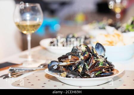 Moules cuites à la vapeur dans une sauce au fromage. Moules en coquilles dans le bol avec vin blanc sur la table. Banque D'Images