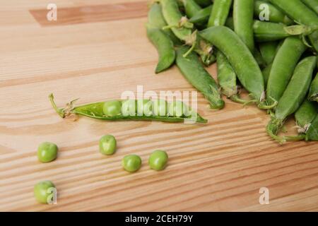 petits pois verts dans des gousses fraîchement cueillies sur du bois. Quelques petits pois verts. Petits pois verts frais. Gousses vertes avec des petits pois comme arrière-plan. Banque D'Images