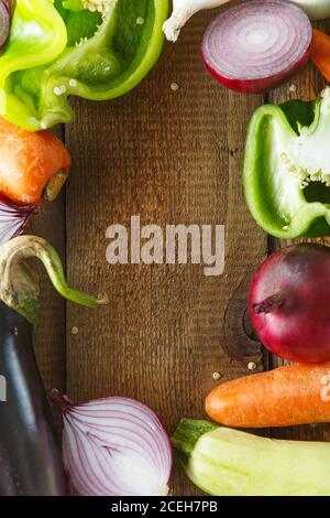 Légumes frais et ingrédients pour la cuisson autour de la planche à découper vintage sur fond rustique, vue de dessus, place pour le texte. Nourriture végétalienne, végétarienne et h Banque D'Images