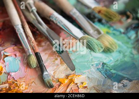 artistes pinceaux et peintures à l'huile sur une palette de bois. macro palette d'artiste, texture peinture à l'huile mélangée dans différentes couleurs et saturation. palette avec pa Banque D'Images