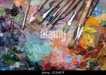 artistes pinceaux et peintures à l'huile sur une palette de bois. macro palette d'artiste, texture peinture à l'huile mélangée dans différentes couleurs et saturation. palette avec pa Banque D'Images