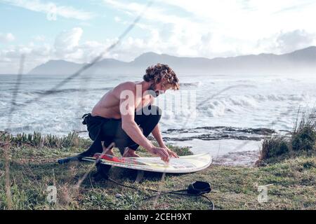 Jeune homme nettoyant planche surf Banque D'Images