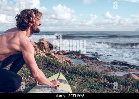 Jeune homme nettoyant planche surf Banque D'Images