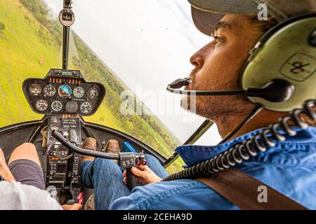 Jock au bâton de contrôle de son hélicoptère Robinson R44 Raven dans le territoire du Nord, en Australie Banque D'Images