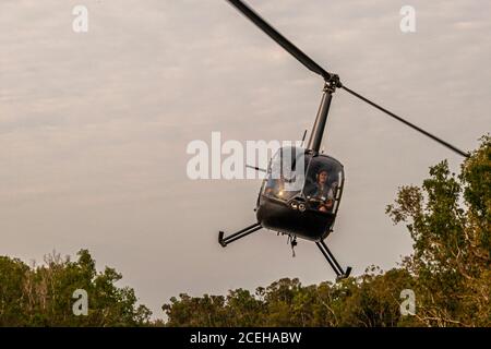 Jock au bâton de contrôle de son hélicoptère Robinson R44 Raven dans le territoire du Nord, en Australie Banque D'Images