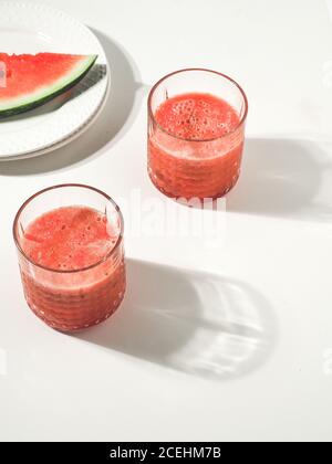 Deux verres de smoothie frais rouge melon d'eau sur table blanche. Copier l'espace. Minimalisme. Banque D'Images