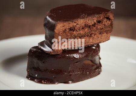 L'alfajor au chocolat sur une assiette blanche sur une table en bois et arrière-plan sombre Banque D'Images