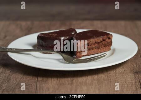 L'alfajor au chocolat sur une assiette blanche sur une table en bois et arrière-plan sombre Banque D'Images