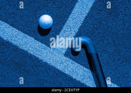 Bâton de hockey sur gazon et balle sur gazon. Filtre de couleur bleu Banque D'Images