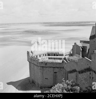 France, années 1950, vue historique du Mont-Saint-Michel, Normandie, une île marémotrice et commune montrant un coin de la forteresse entourant l'ancienne abbaye bénédictine. L'île se trouve au large de la côte nord-ouest de la France, à l'embouchure du fleuve Couesnon. Le mont St Michael's à Cornwall, au Royaume-Uni, est semblable au Mont-Michel. Banque D'Images