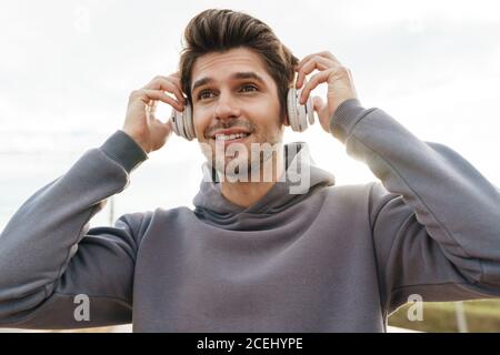 Gros plan sur un sportif satisfait qui utilise un casque et qui sourit tout en souriant en plein air Banque D'Images