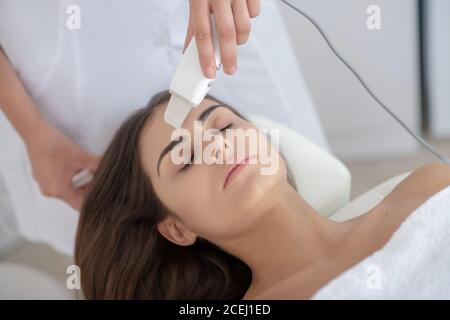 Femme aux cheveux foncés ayant un traitement de peau au laser dans la clinique Banque D'Images
