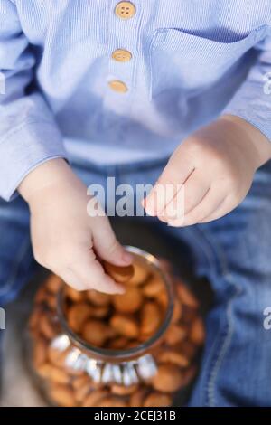 La main de l'enfant tendant la main pour prendre un pot de cookies Banque D'Images