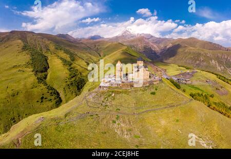 Belle vue de dessus de drone à Tsminda Sameba ou église de la Sainte Trinité près du village de Gergeti en Géorgie et de la haute montagne Kazbek, Caucase Banque D'Images