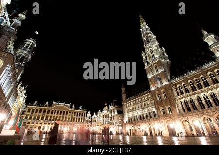 Vue panoramique nocturne de la grande place de Bruxelles ( Belgique ) sous la pluie. Exposition longue durée. Le grand palais à droite, son style baroque Banque D'Images