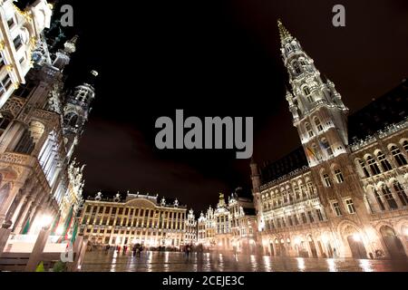 Vue panoramique nocturne de la grande place de Bruxelles ( Belgique ) sous la pluie. Exposition longue durée. Le grand palais à droite, son style baroque Banque D'Images