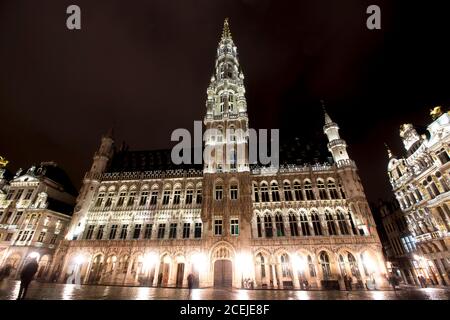 Vue panoramique nocturne de la grande place de Bruxelles ( Belgique ) sous la pluie. Exposition longue durée. Le grand palais à droite, son style baroque Banque D'Images