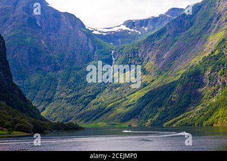 Paysage pittoresque vue sur les sommets de montagne avec des pistes vertes et la surface de l'eau et des nuages de plumes sur le ciel en arrière-plan par temps ensoleillé Banque D'Images