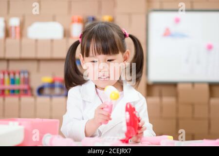 oung fille prétendre jouer comme dentiste regardant le patient à la maison Banque D'Images