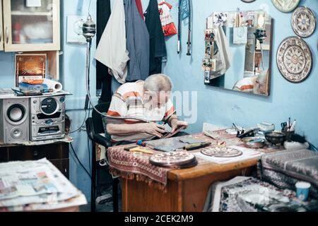 Istanbul, Turquie - août 17 2018 : maître adulte assis sur le lieu de travail dans la boutique et la plaque de gravure Banque D'Images