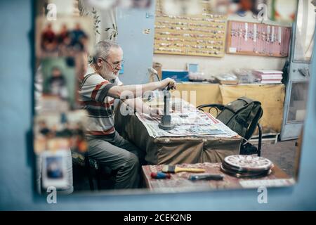 Istanbul, Turquie - août 17 2018 : maître adulte assis sur le lieu de travail dans la boutique et la plaque de gravure Banque D'Images