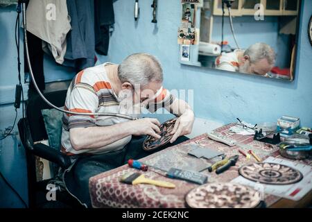 Istanbul, Turquie - août 17 2018 : maître adulte assis sur le lieu de travail dans la boutique et la plaque de gravure Banque D'Images