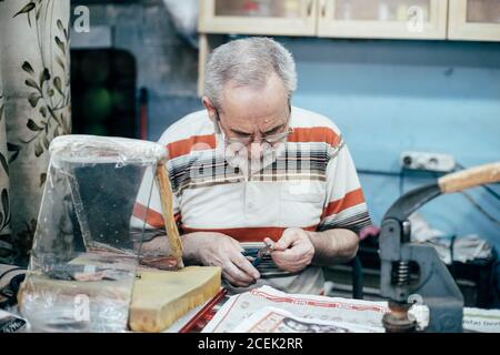 Istanbul, Turquie - août 17 2018 : maître adulte assis sur le lieu de travail dans la boutique et la plaque de gravure Banque D'Images