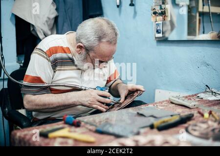 Istanbul, Turquie - août 17 2018 : maître adulte assis sur le lieu de travail dans la boutique et la plaque de gravure Banque D'Images