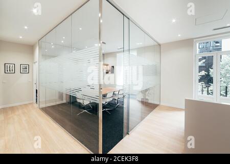 Vue de la table et des chaises derrière la cloison en verre dans bureau moderne Banque D'Images