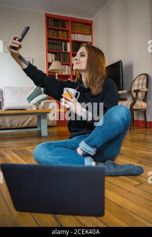 Femme prenant le selfie assis sur le sol Banque D'Images